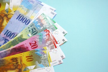 Swiss franc banknotes on blue background. The current francs money bills lies in big amount