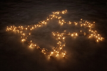 A star constellation map formed with tiny LED fairy lights on a smooth dark fabric surface.