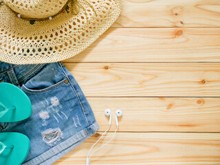 Denim Shorts, sun hat and flip-flop on wooden background