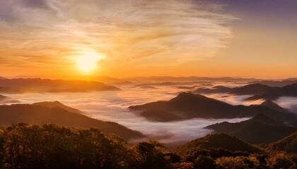 golden sunrise over misty mountain range with rolling hills glowing clouds and layers of fog creating a serene panoramic landscape