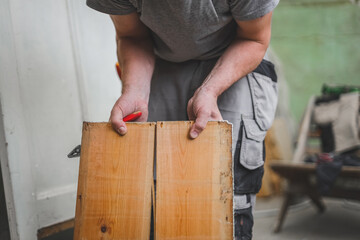 One young worker holds two wooden boards.