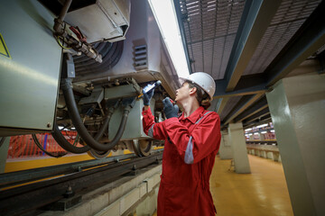 Technician inspecting train components in underground facility during daytime