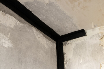 Concrete wall and ceiling in a panel apartment, seams from leaks sealed with black waterproofing,...