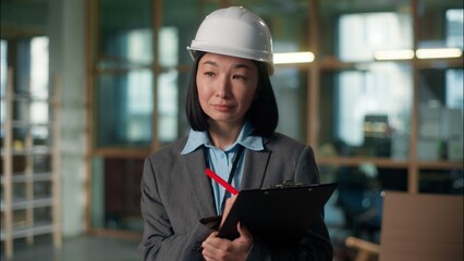 Builder woman Asian girl architect inspector in hard hat inspecting building construction checklist writing document industry plan Japanese Korean Chinese female engineer expert developer foreman work