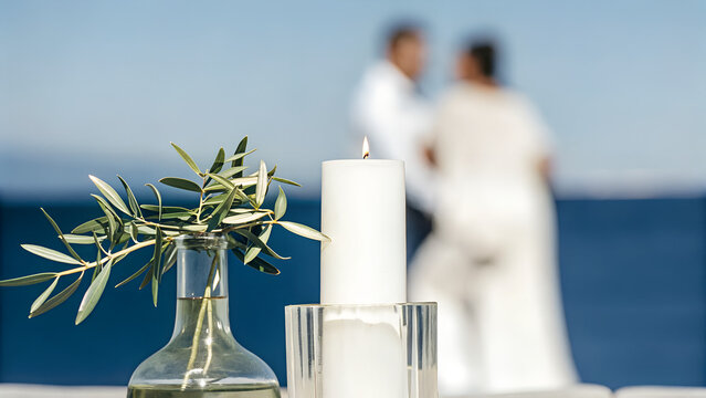 Newlywed couple embracing by the sea with candle and greenery in foreground - Powered by Adobe