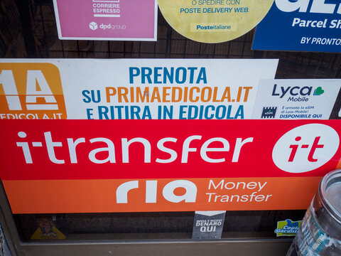 Colorful service stickers crowding newsstand window, displaying diverse money transfer and shipping options for customers