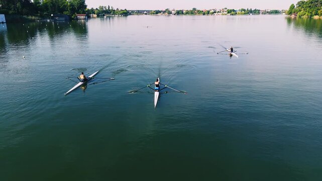 Cinematic Aerial View Of Rowers. National team precise movements slice through the water In beautiful  weather conditions. Rowers paddling on the lake near the forest. The Athletes Training Routine.