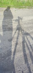 Shadow of person with bicycle on rural dirt road in sunlight