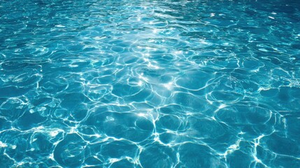 Obraz premium Sparkling clear turquoise water fills a swimming pool under the bright sunlight. The sunlight creates shimmering reflections on the surface, enhancing the tranquil environment.
