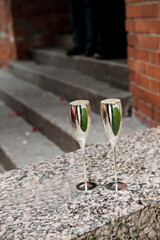 Two silver-colored champagne glasses placed on the ground.