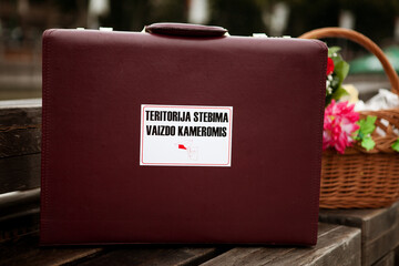 A brown travel suitcase with an information sticker attached to it.