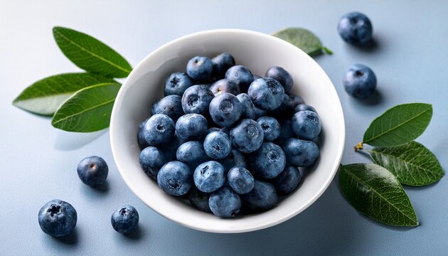 fresh blueberries in a white bowl with leaves