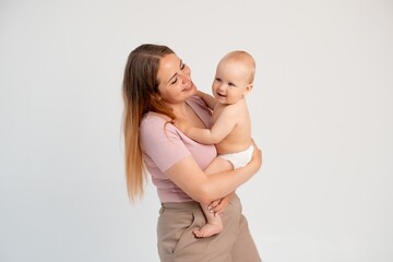 mother and baby, mother gently kisses and hugs her baby in diapers on a white isolated background, mother's love and care, space and room for text