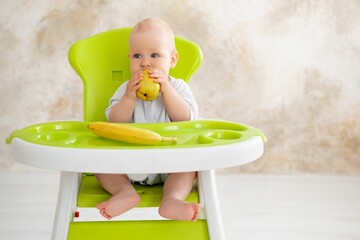 feeding a baby boy with fruit puree in a green high chair, baby food