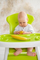 feeding a baby boy with fruit puree in a green high chair, baby food