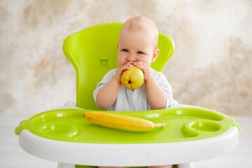 feeding a baby boy with fruit puree in a green high chair, baby food