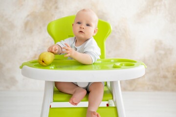 feeding a baby boy with fruit puree in a green high chair, baby food