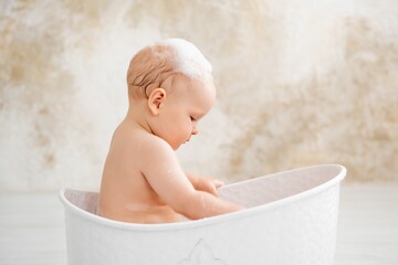 baby in the bathtub, boy bathing or washing in a bathtub with bath foam, baby's hygiene.
