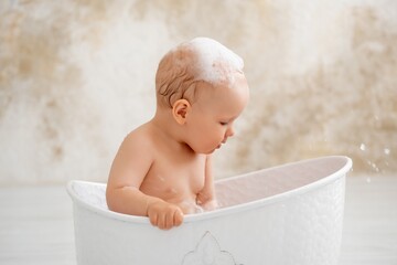 baby in the bathtub, boy bathing or washing in a bathtub with bath foam, baby's hygiene.