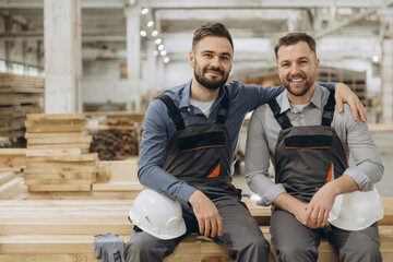 Carpenters sitting on wood planks in lumber warehouse