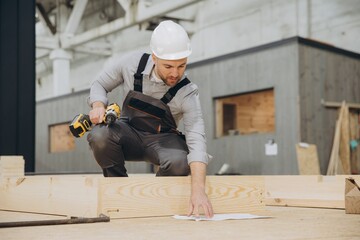 Carpenter building wooden structure using cordless drill in workshop