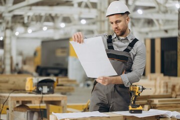 Construction worker reading blueprint in modular building factory