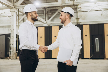 Engineers shaking hands at modular building construction site