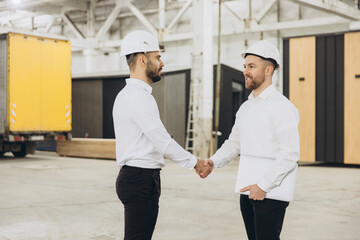 Engineers shaking hands in modular building factory