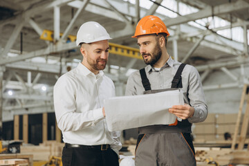 Engineers reading blueprint in modular building factory