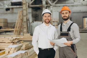 Engineers and construction workers discussing plans in modular building factory