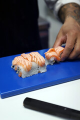 experto en sushi elaborando de sushi de salmón ahumado y arroz para servirlo en una tabla especial de sushi