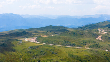 Panoramic view of Jahorina mountain plateau with winding roads and open grassy hills under soft sky