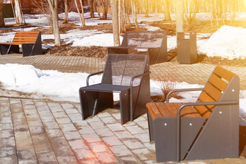 Wooden bench in the spring park. Bright spring sun and snow in the park. Place to rest for a walk. Morning walk..