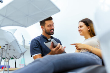 Fototapeta premium Male Dentist Showing Information on Tablet to Female Patient