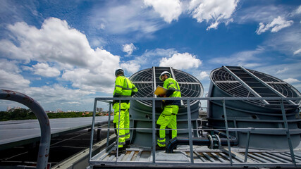Workers inspect rooftop ventilation systems on a sunny day