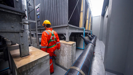Worker inspects cooling system in industrial facility during overcast weather