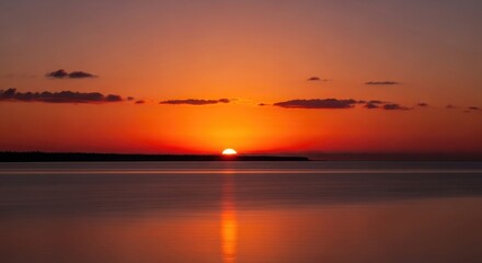 Fototapeta premium Sun Setting Over Calm Water with Orange Sky Reflection