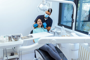 Male Dentist Treating Female Patient’s Teeth