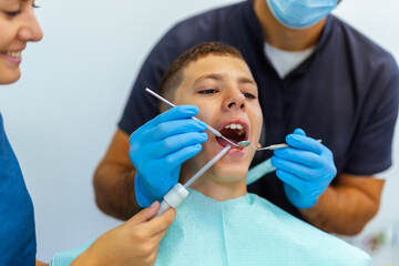 Dentist and Female Assistant Treating Young Boy’s Teeth