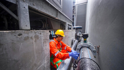 Worker performs maintenance on industrial pipes in a facility during daytime hours