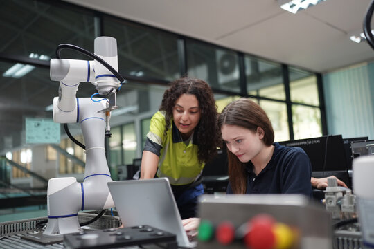 Engineer guides student in robotics lab with autonomous arm and computer
