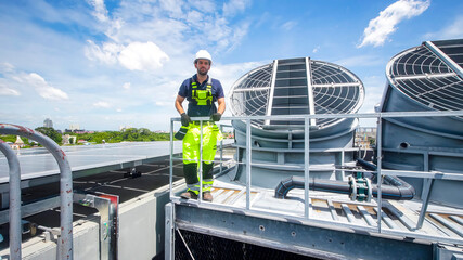 Worker on rooftop cooling system during sunny day in urban area