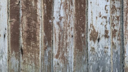 The wooden walls of an ancient Thai house are brown in color; the surface is peeling and has...