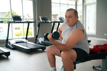 Senior man lifting dumbbell during workout session in fitness center