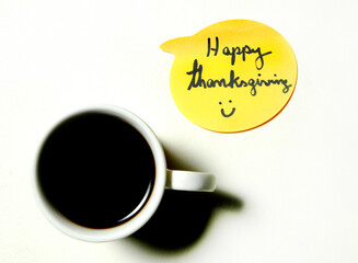 Yellow Happy Thanksgiving emoji or sticker, and a cup of coffee on the left, on a white background.