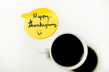 Yellow Happy Thanksgiving emoji or sticker, and a cup of coffee on the right, on a white background.