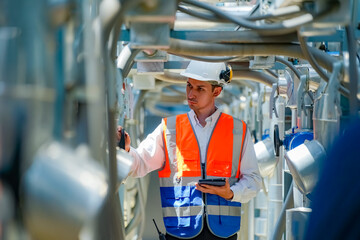 Worker examines equipment in industrial facility during daylight hours