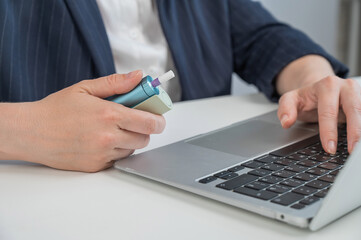 Business woman smoking an electronic cigarette while working on a laptop. Tobacco heating system. 