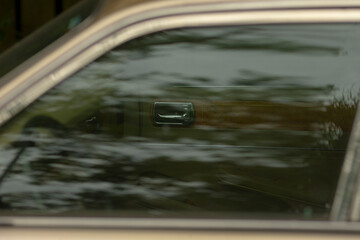 This is a closeup view of a cars window, showcasing a beautiful reflection of trees that can be...