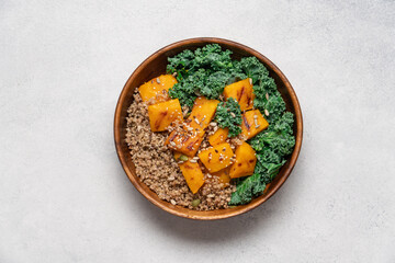 Autumn Harvest Bowl with Quinoa, Green Buckwheat, Roasted Pumpkin, and Kale in Wooden Bowl on Light Background. Healthy Vegan Fall Meal